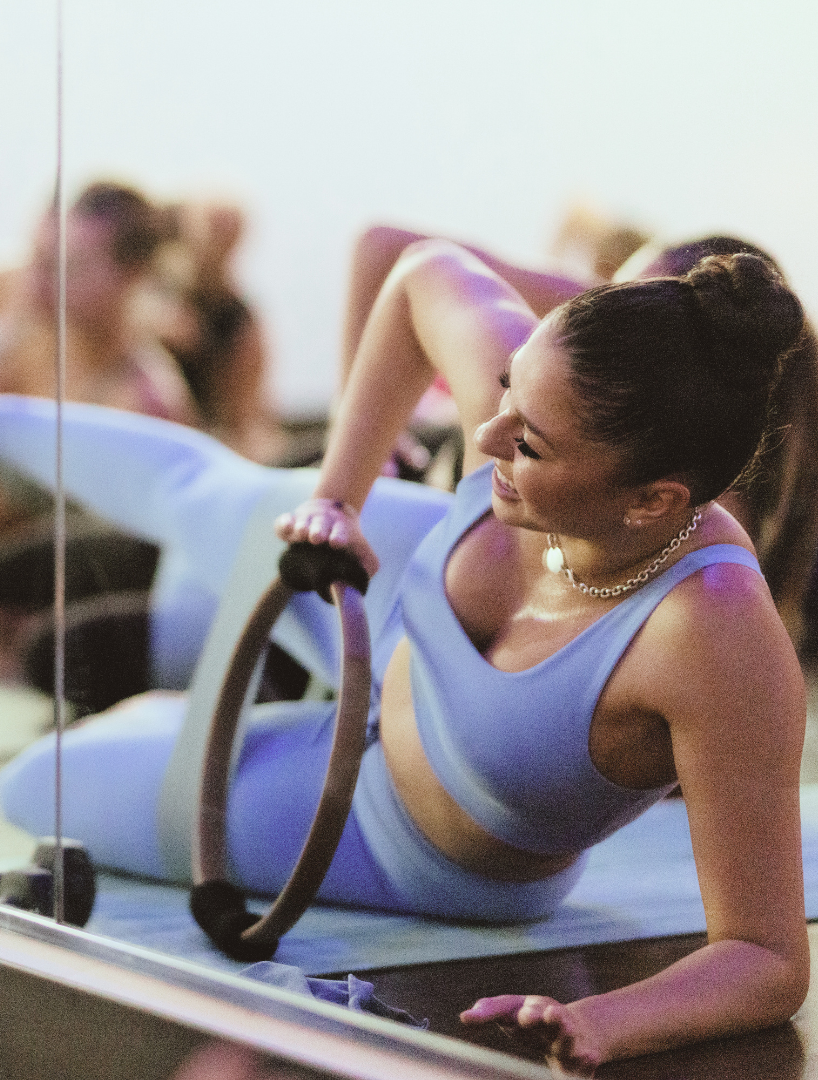Student practicing side-lying core and oblique strengthening with a Pilates ring during barre training