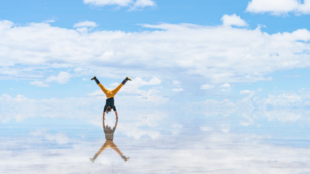 hand-stand with sky mirroring on the sand