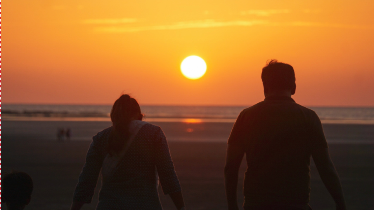 Parent and teenage child on the beach together at sunset, symbolizing connection, support, and moving forward as a family.