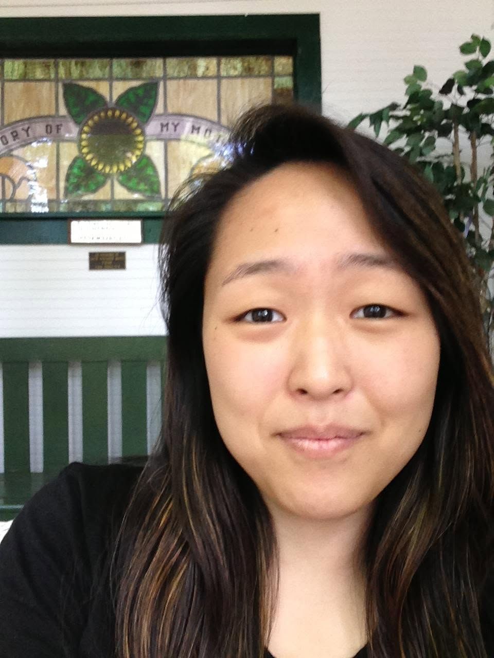 Jane Kim Yu in soft light by a stained-glass window