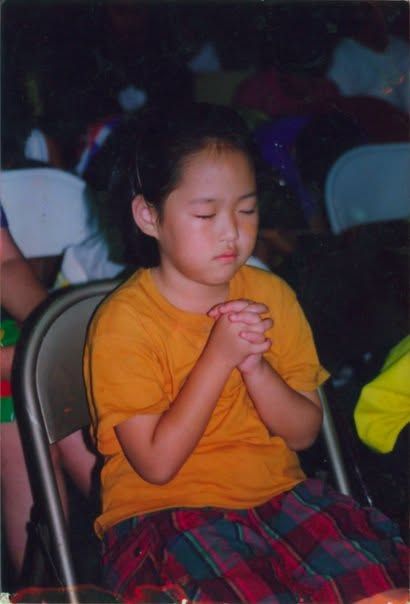 Jane as a child, hands clasped, eyes closed