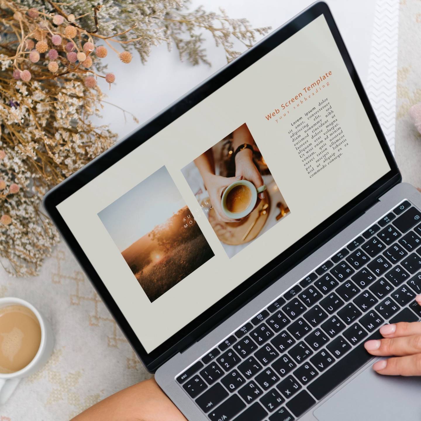 Laptop showing a website design beside a coffee and flowers