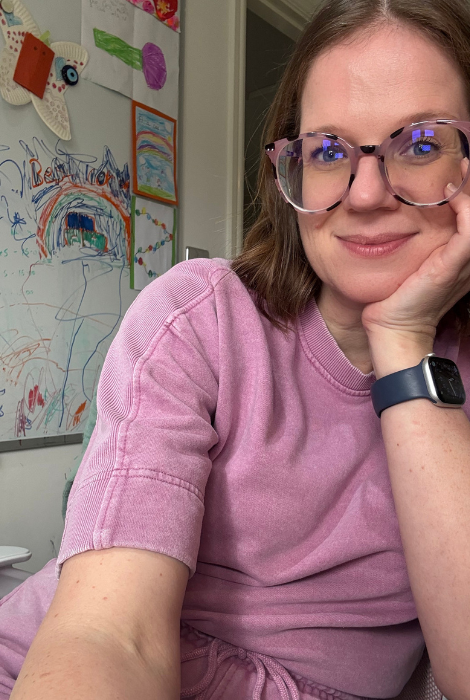 Dr Nicola Sutton smiling at home with children's artwork on the wall behind her