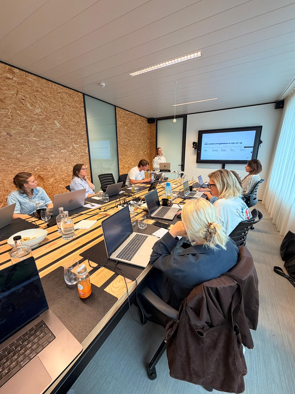Emma Declerck begeleidt een AI-strategiesessie met een managementteam rond de tafel