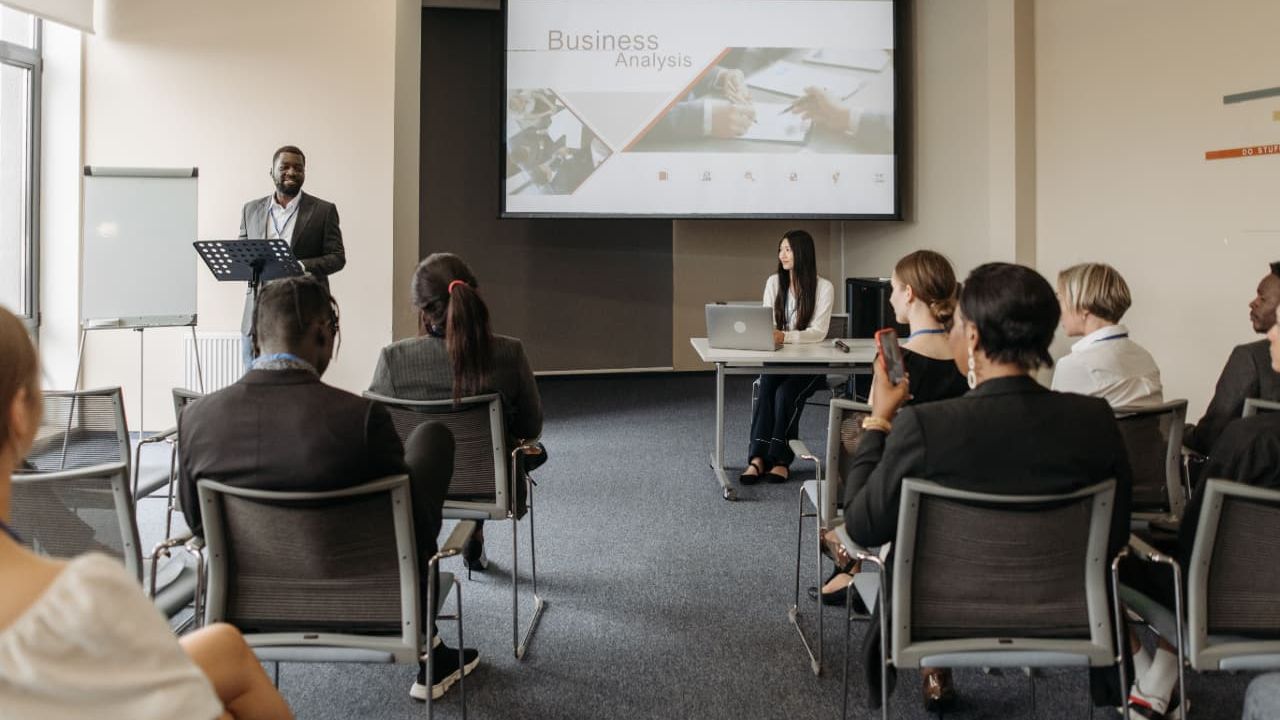 A speaker standing at a podium, presenting to a group in a conference room, illustrating calm and controlled presentation delivery