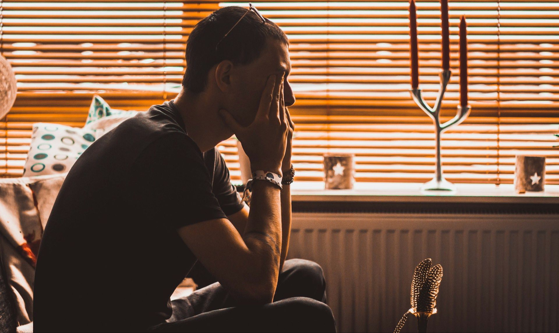 Man sitting with elbow on knees and hands covering face and eyes