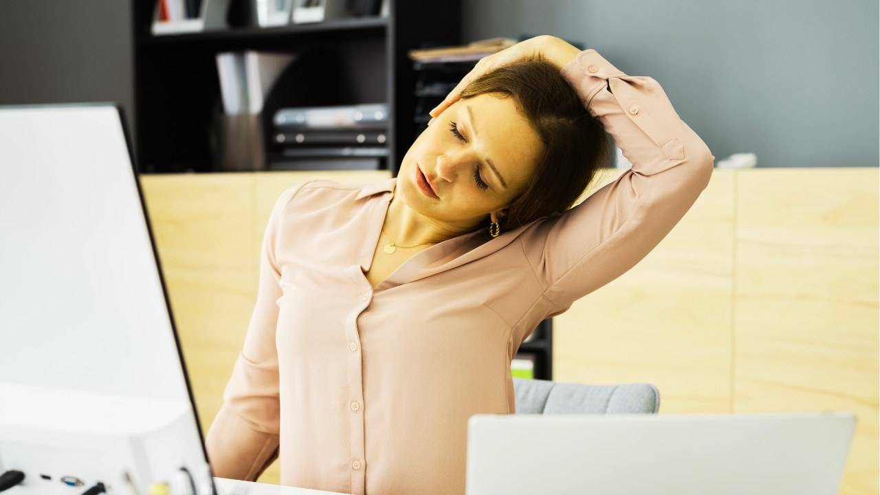 Woman doing a seated chair yoga neck stretch at her desk