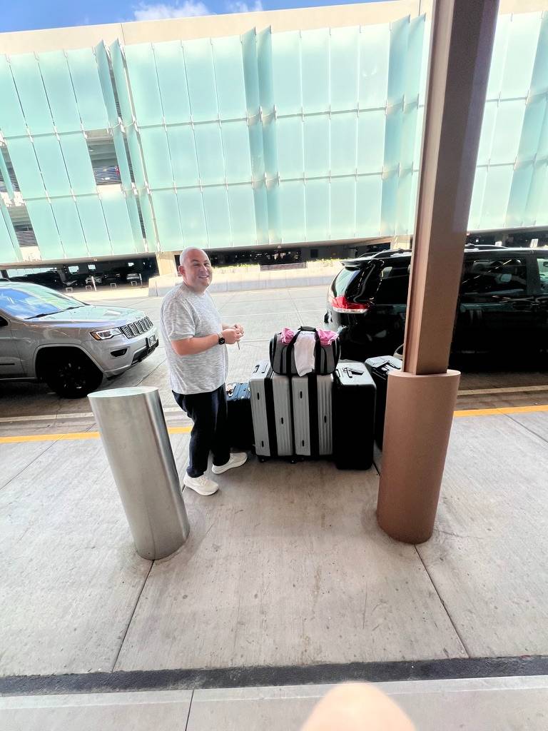 Sam standing beside our luggage at the airport in August 2024