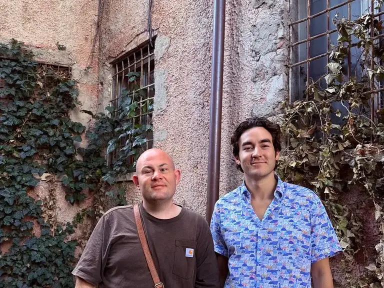 Sam on the left and Spencer on the right, beside an ivy-covered building