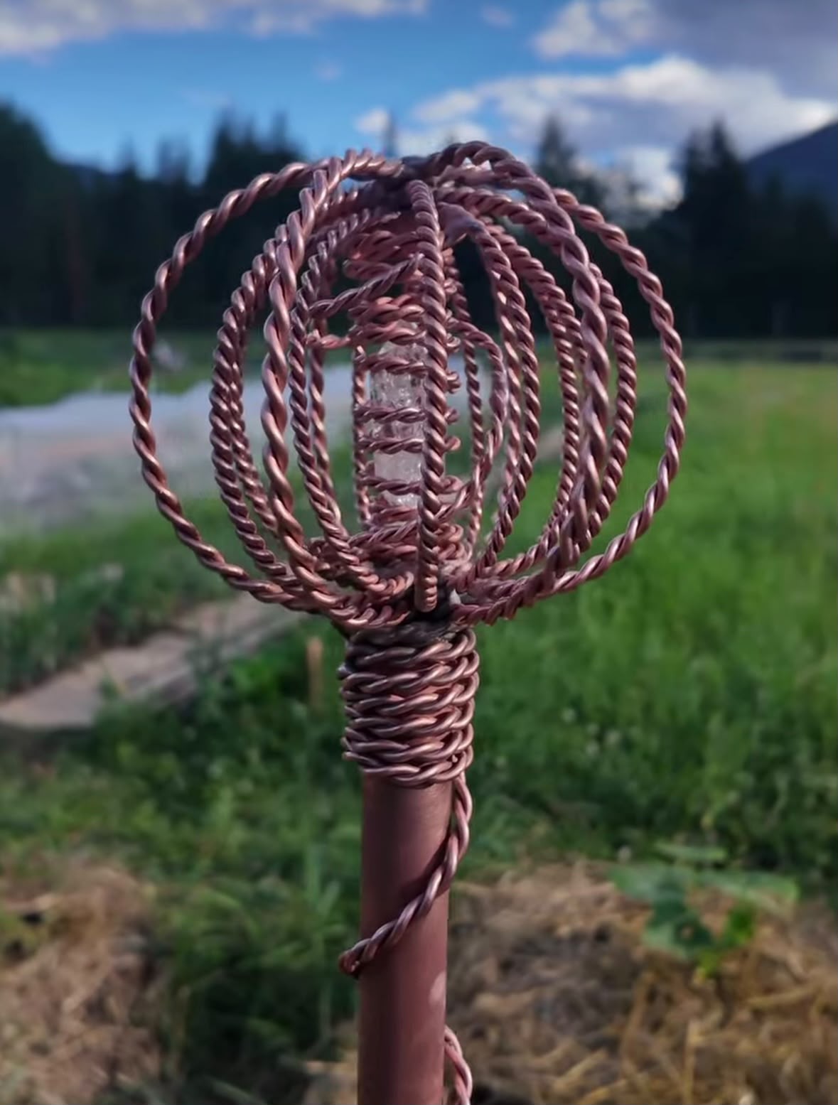 The woven copper crown and quartz heart of a Homestead Harmonizer Antenna System above the field