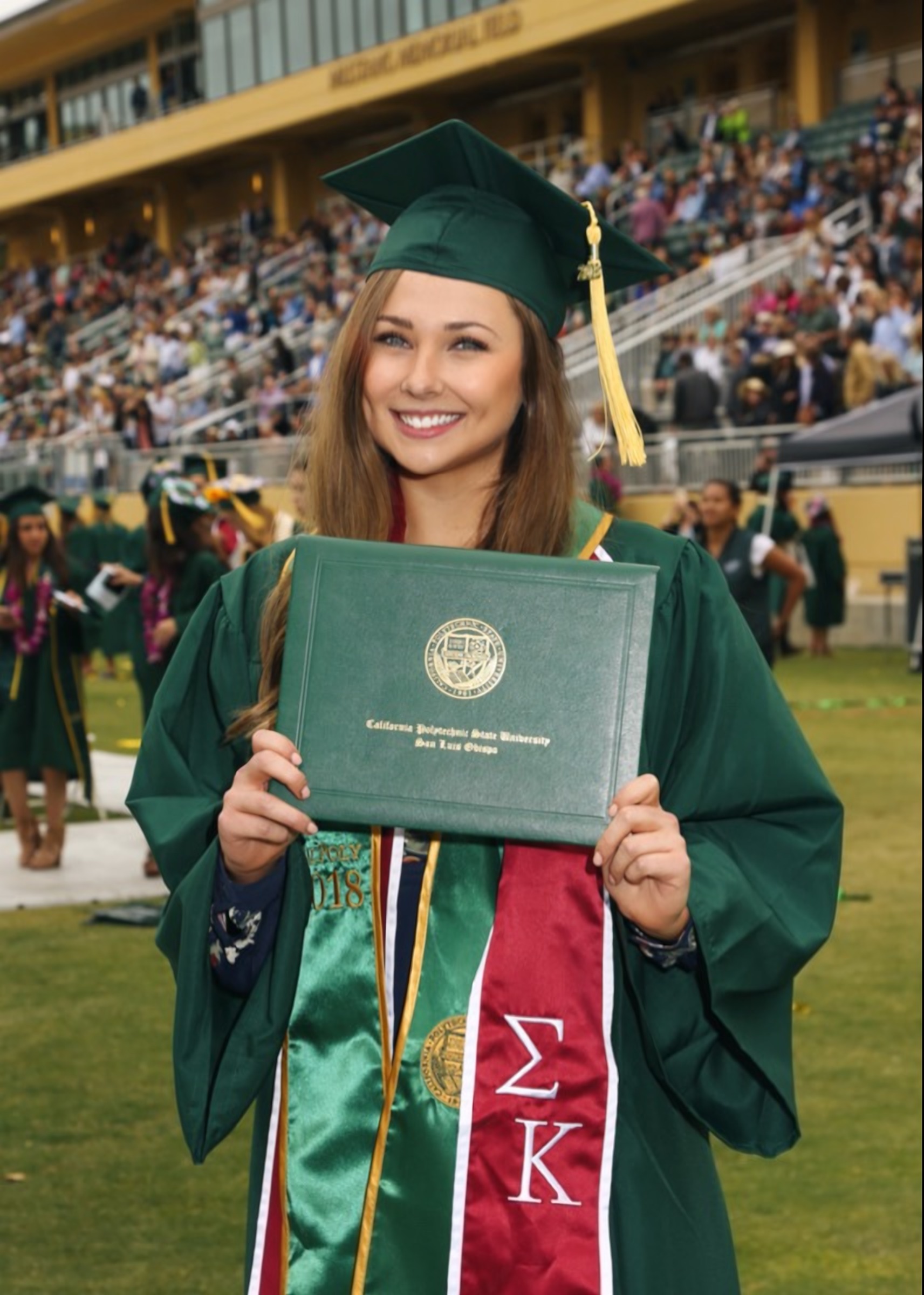 Lauren at her 2018 college graduation, holding her diploma and smiling