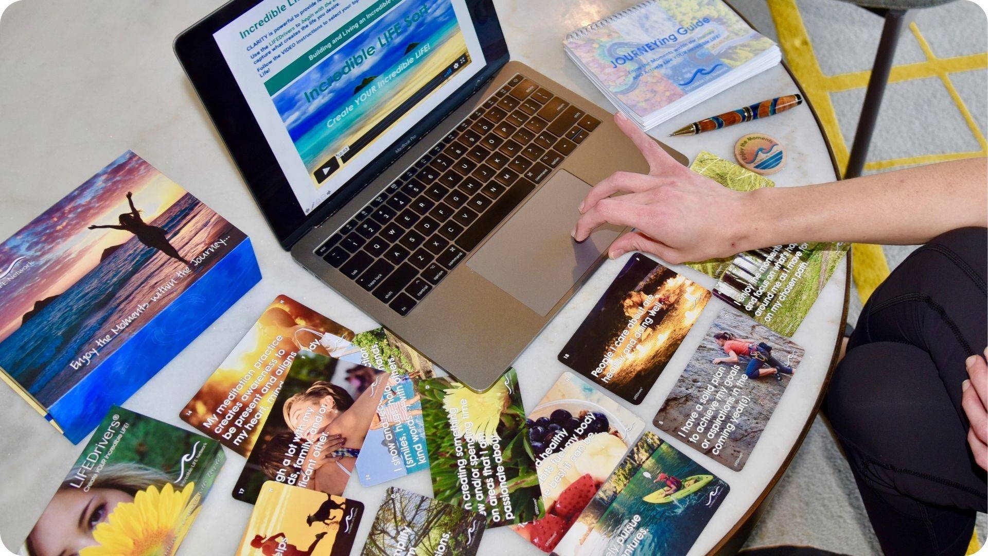 LIFEDrivers cards next to a laptop showing the online Explorer Experience course, with the JOURNEYing Guide workbook nearby