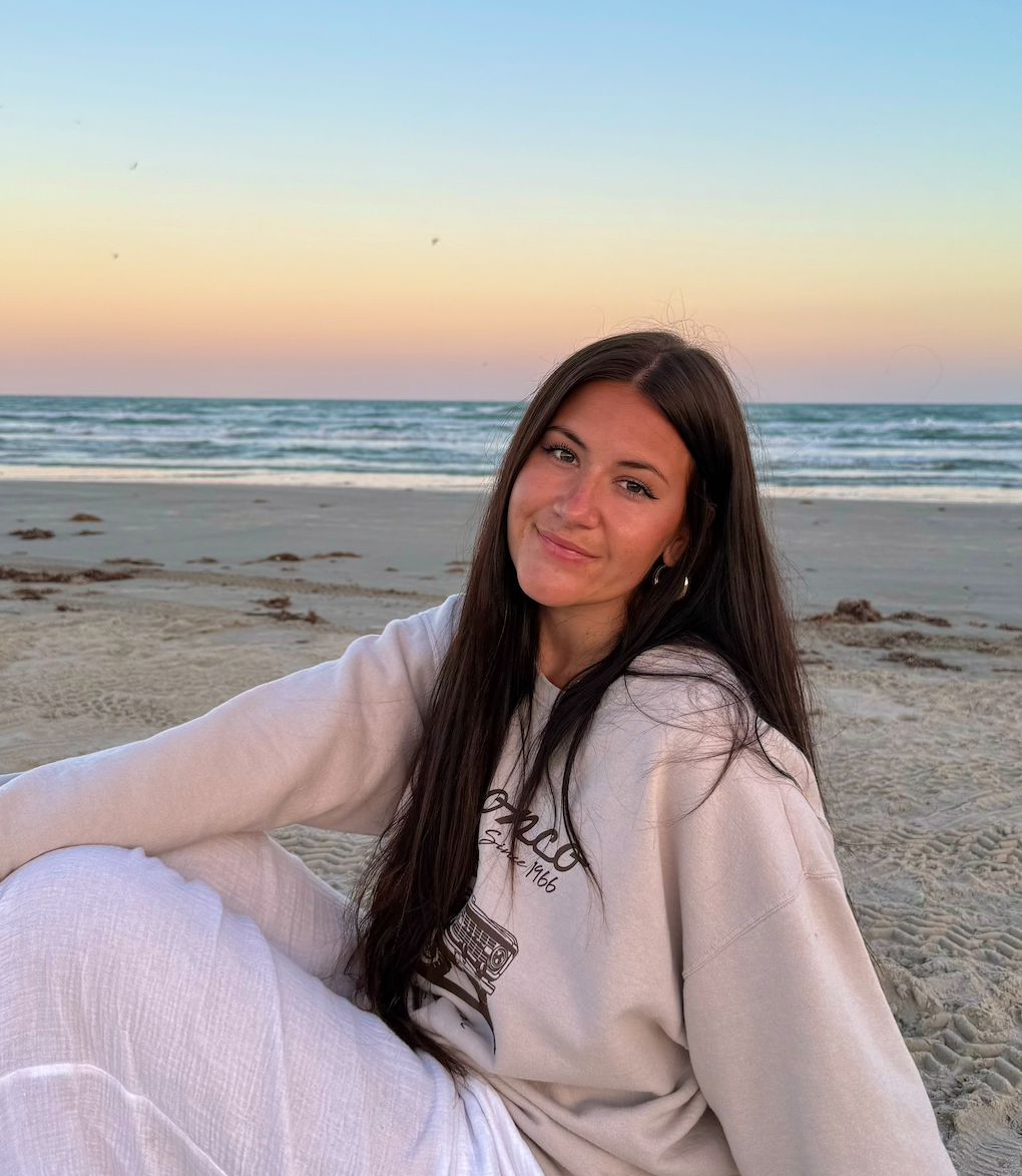 Makenzie Barton, founder of Incredible LIFE Network, sitting on the beach at sunset