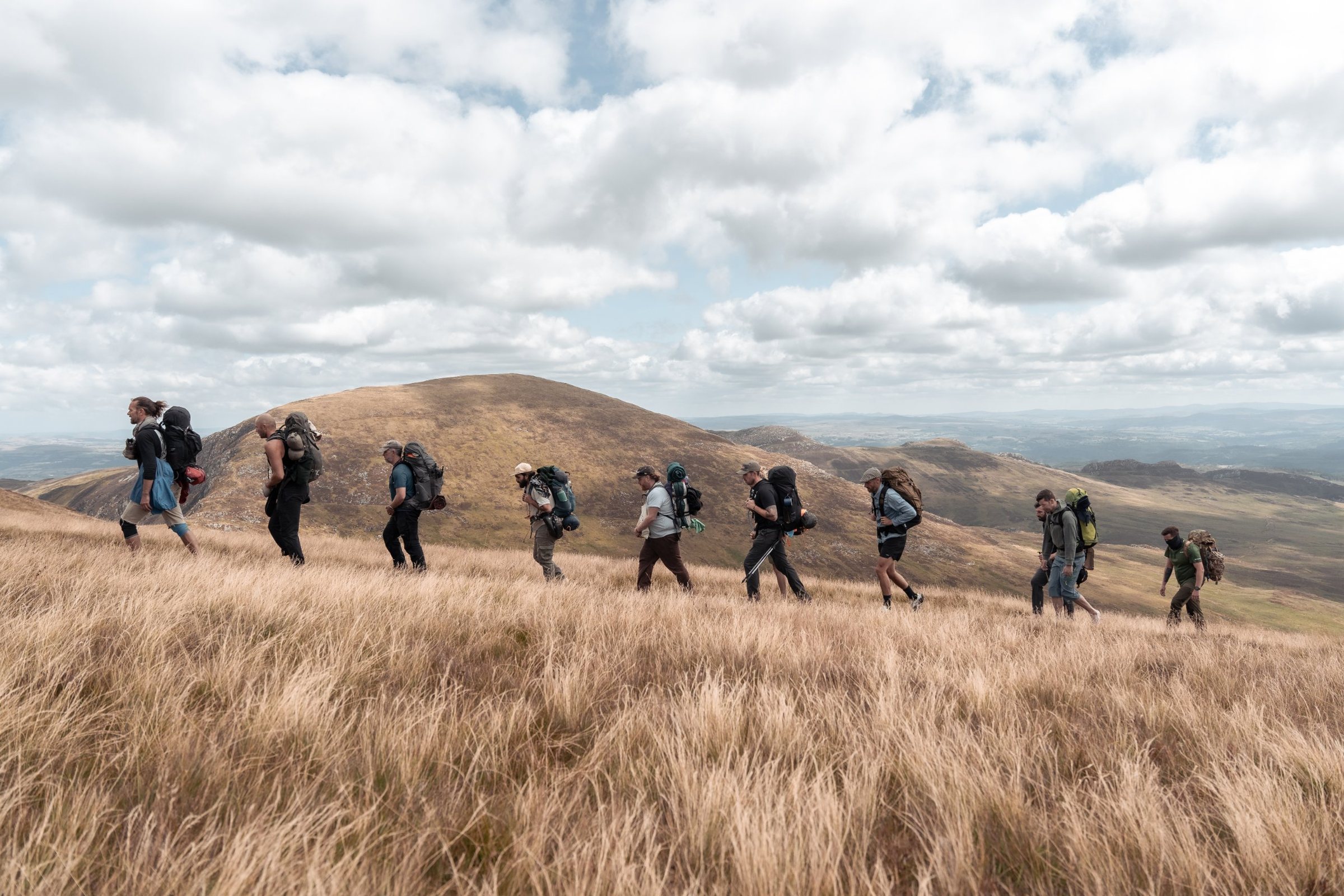 A line of men with packs crossing a hillside