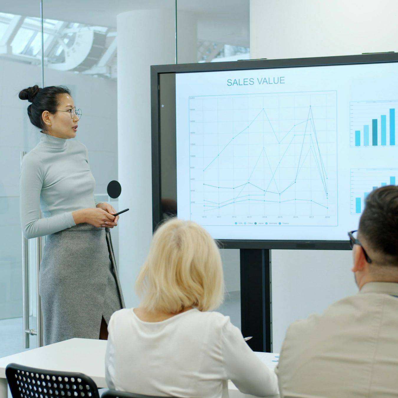 lady with bun and business outfit presenting sales value chart 