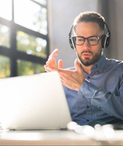 Online coach wearing a headset during a virtual coaching session on a laptop.