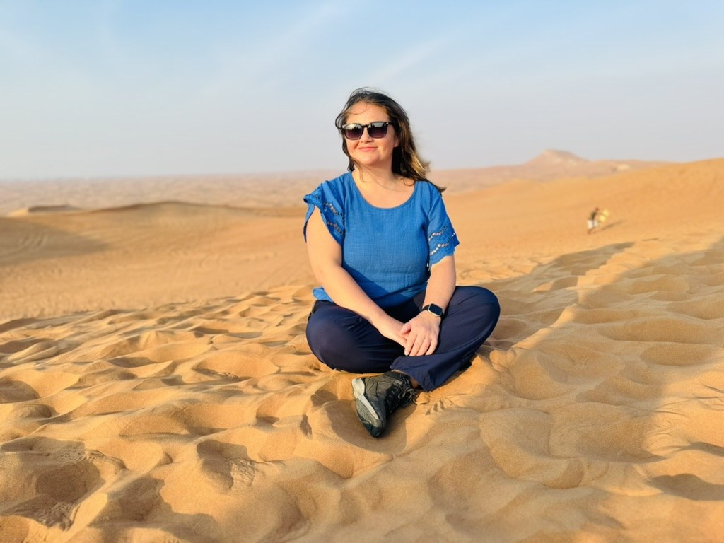 River sitting on a sand dune in the desert outside Dubai