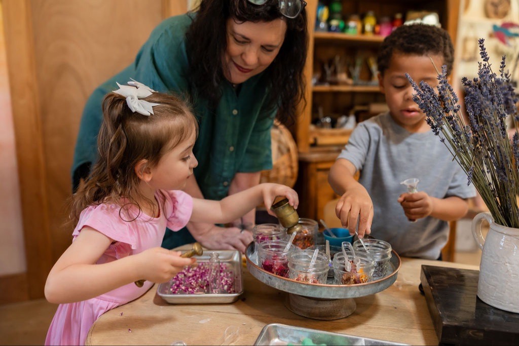 Sally Haughey watching two children scoop dried flower petals into small jars
