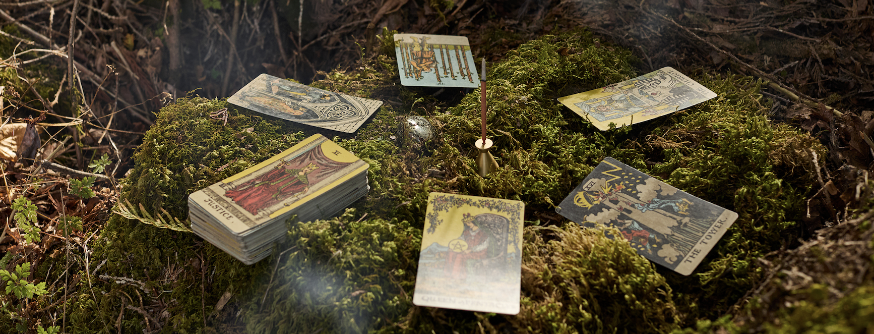 Cartes de tarot disposées en cercle sur la mousse, autour d'un bâton d'encens