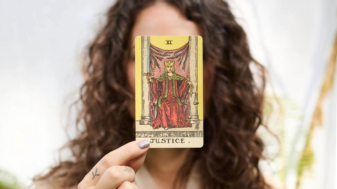 Le Passage, rituel annuel 2027 : une main tient la carte de la Justice