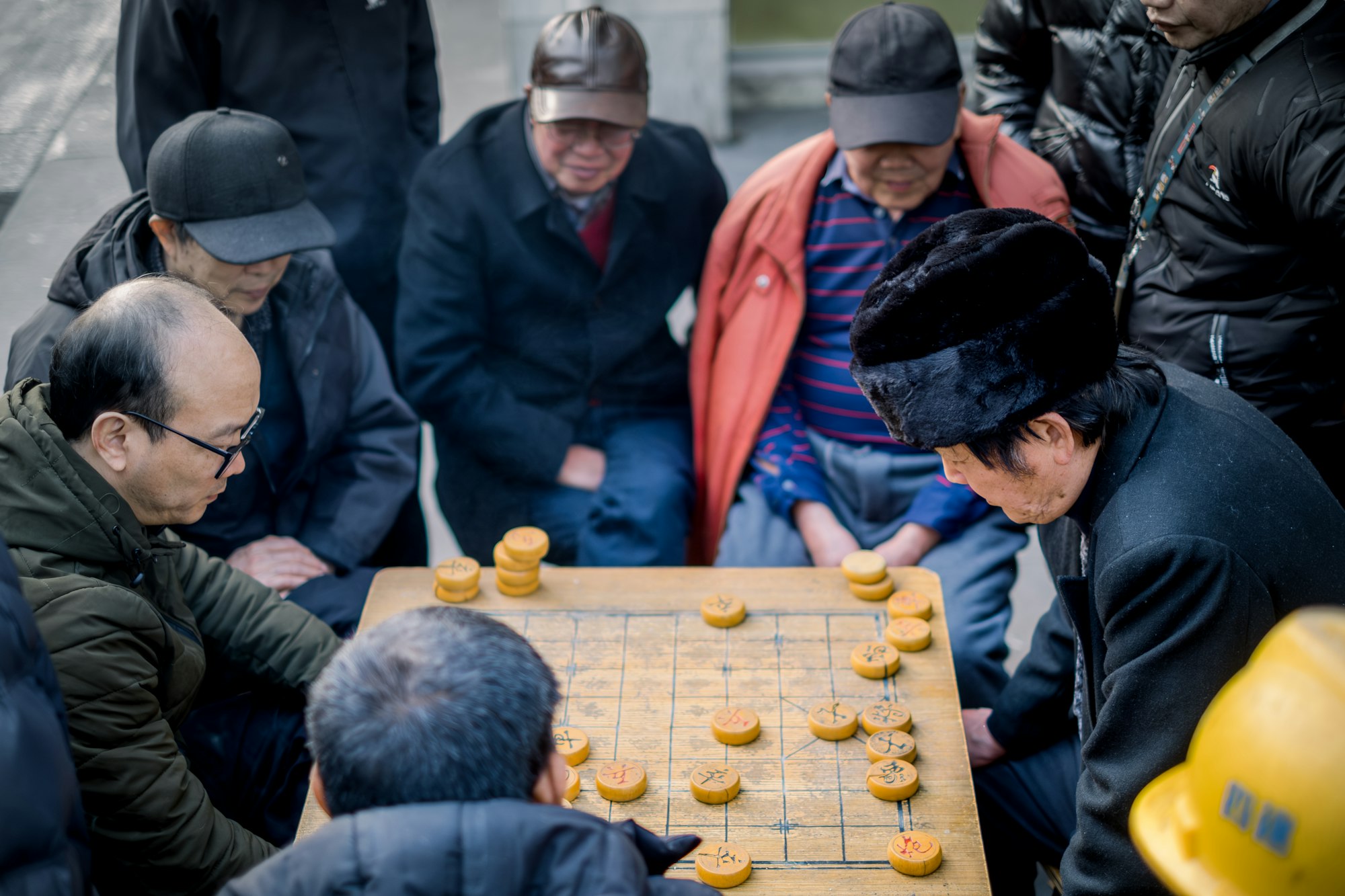 Older men gathered around a Chinese chess board outdoors