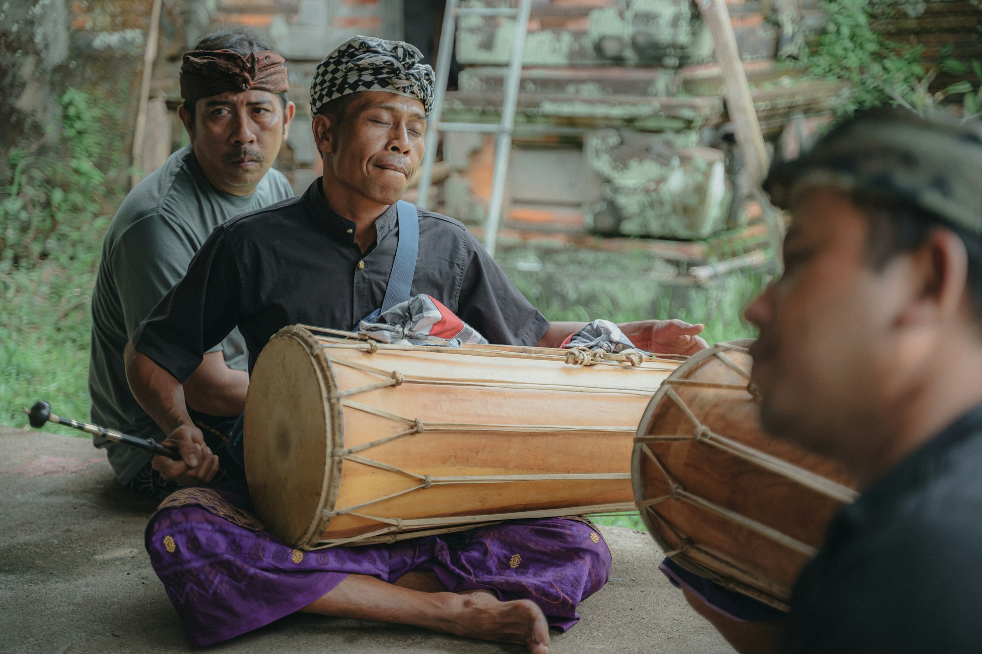 Men sitting on the ground playing traditional drums together