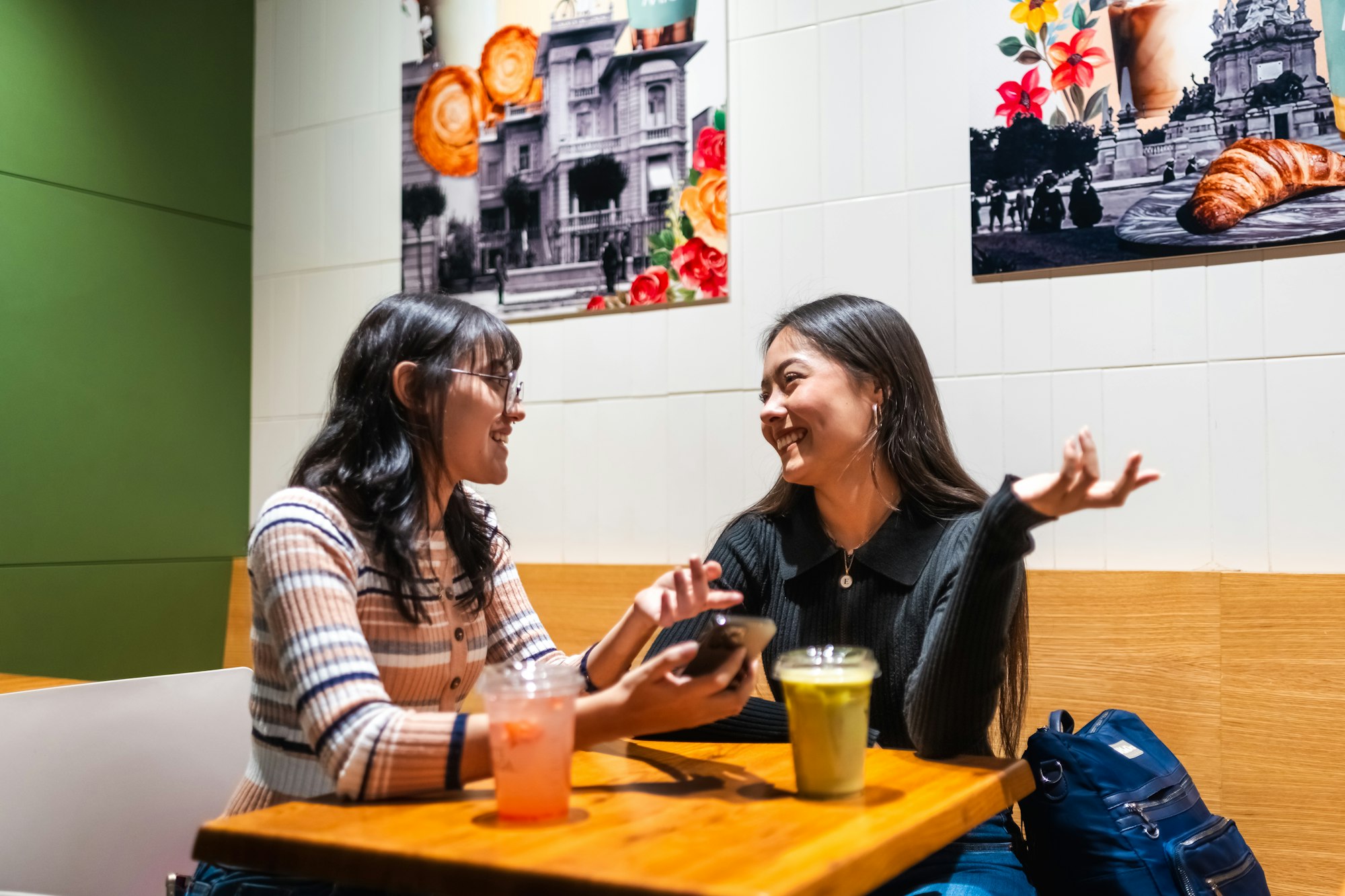Two young women talking at a cafe table