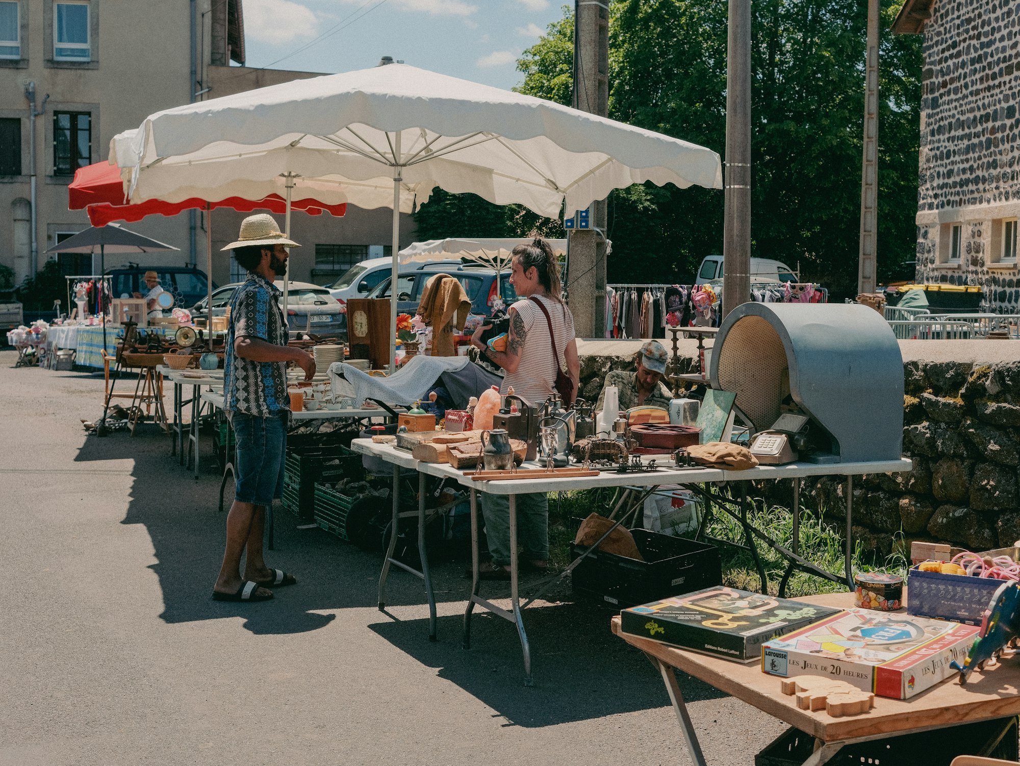 A vendor in a straw hat talking with a woman at a flea market