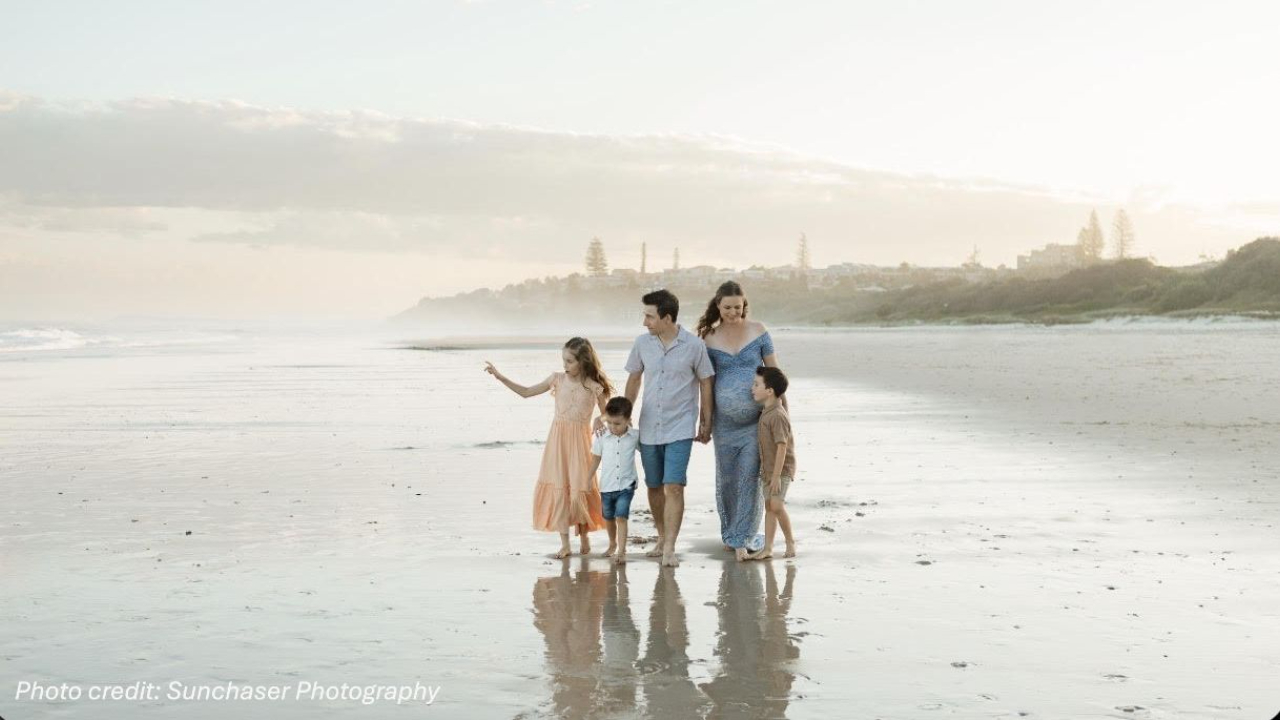 Family walking on beach with 3 children, soon transitioning to 4