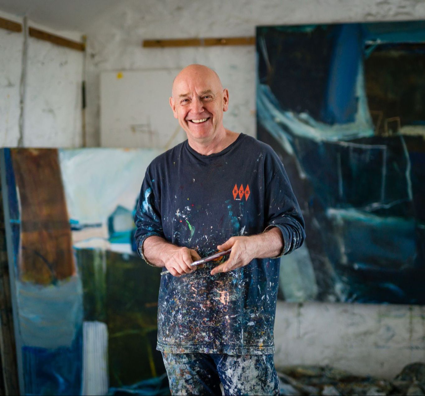 Black and white photo of David painting dynamically on a large canvas in his studio, using expressive, sweeping brushstrokes.