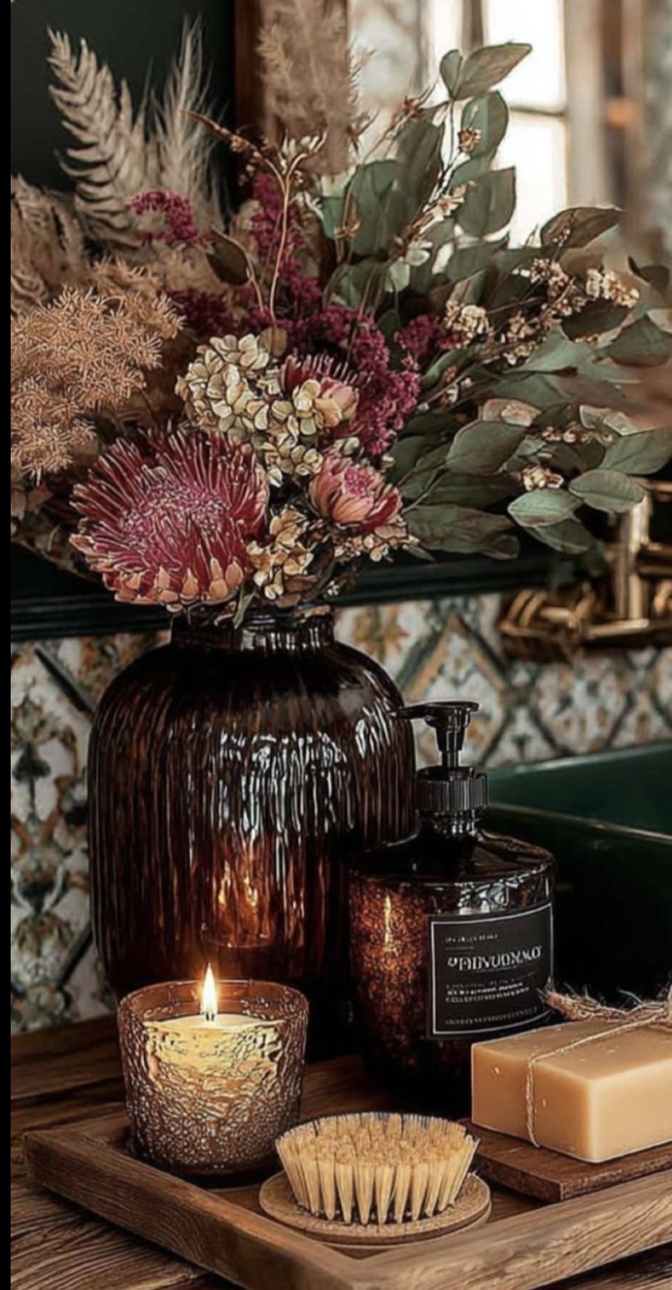 Dried flowers in an amber vase beside a lit candle