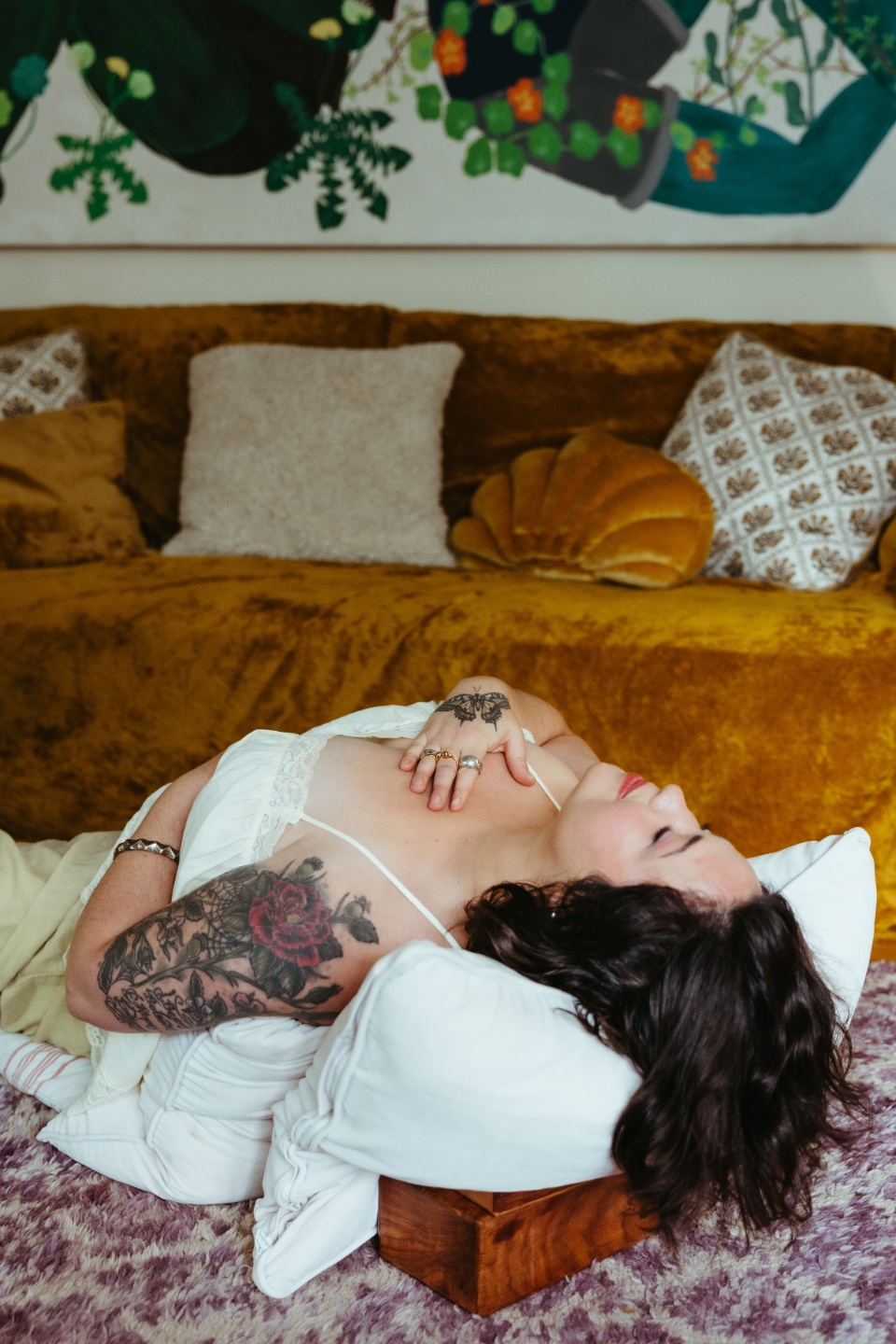 Woman's hands resting on her knees in a ritual floral bath with rose petals, embodying sacred feminine self-care and Ayurvedic nourishment