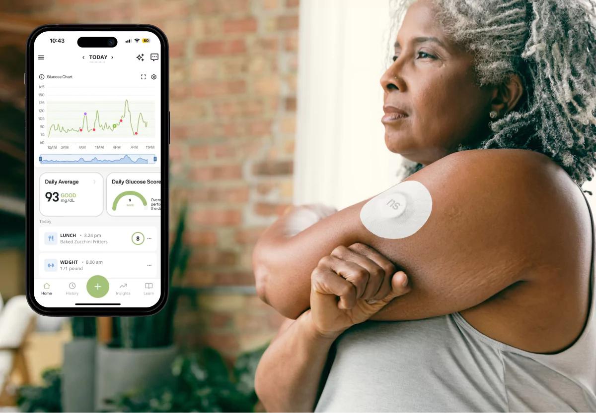 Woman using a continuous glucose monitor with glucose data displayed on a smartphone