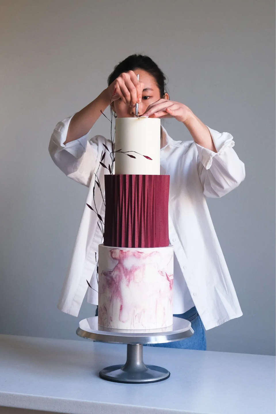 Merul placing florals on a three-tier origami wedding cake