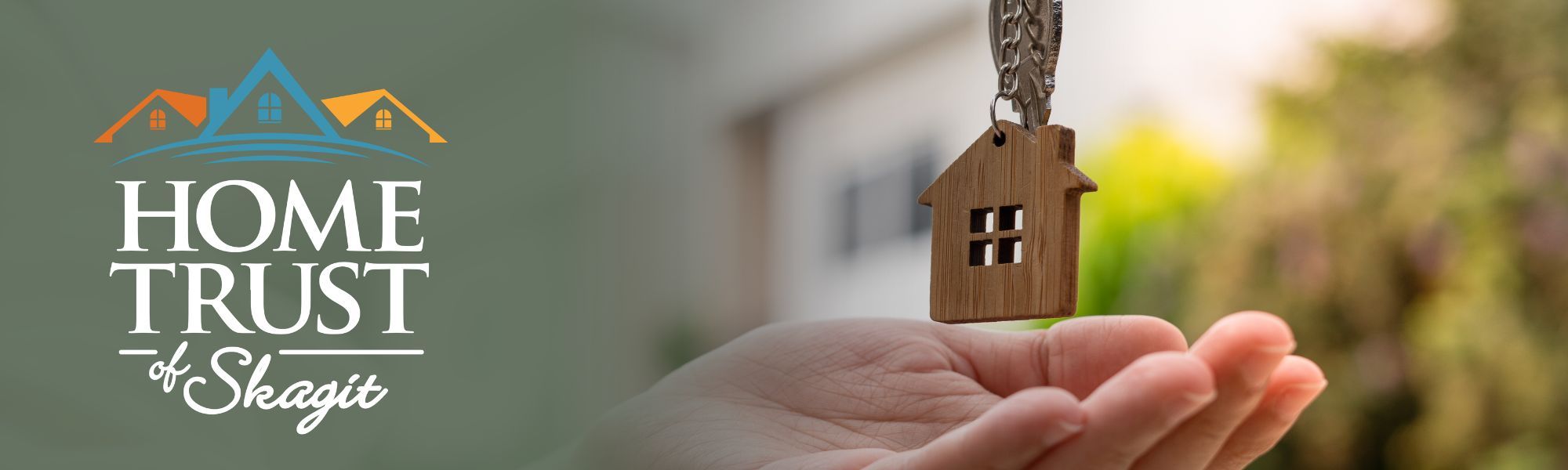 Home Trust logo on a banner with image of a hand waiting to catch a house shaped keychain.