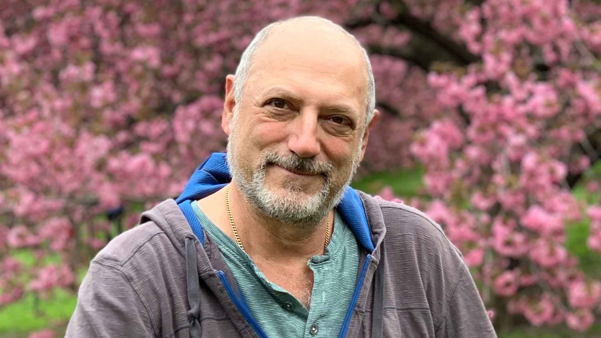 Photo of Leslie smiling in front of cherry blossoms in Central Park, NYC