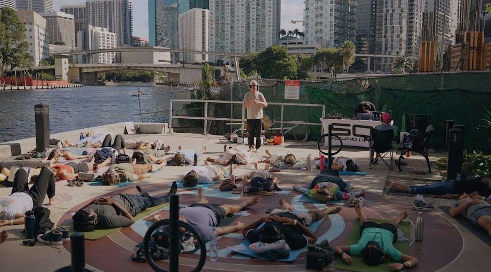 A large outdoor breathwork class on mats beside the Miami skyline