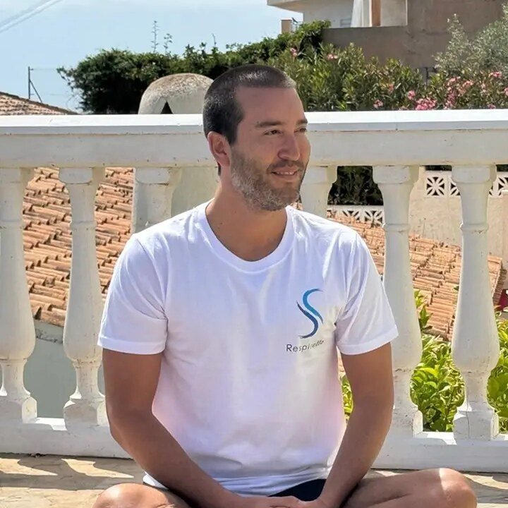 Christian Bello, Pillar 3 graduate, seated cross-legged on a sunny terrace