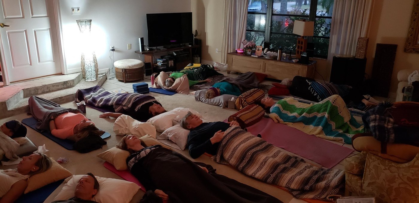 A group lying on mats under blankets in a living room during a dry rebirthing session