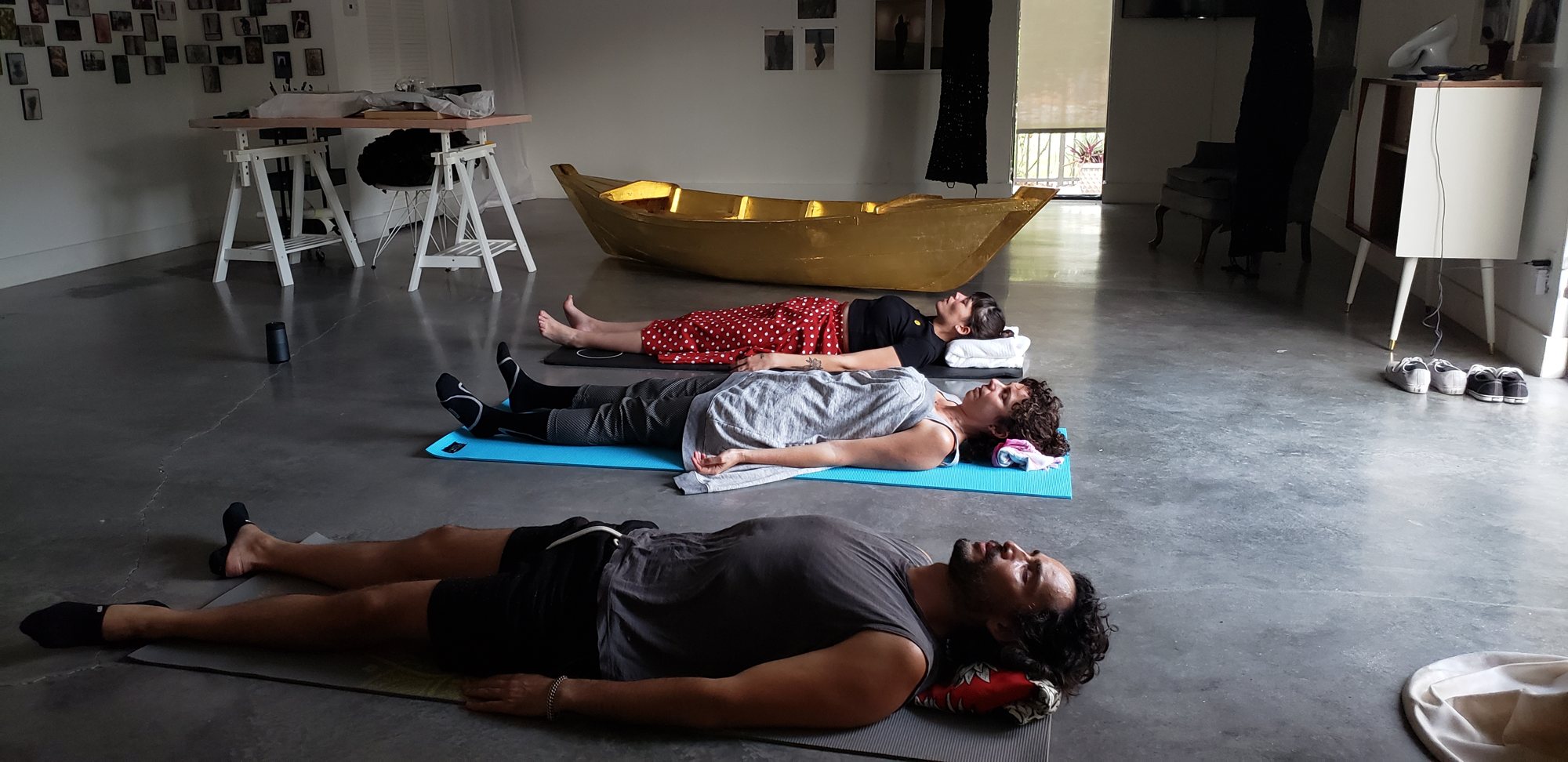 Three people resting on mats during a breathwork session in a bright loft