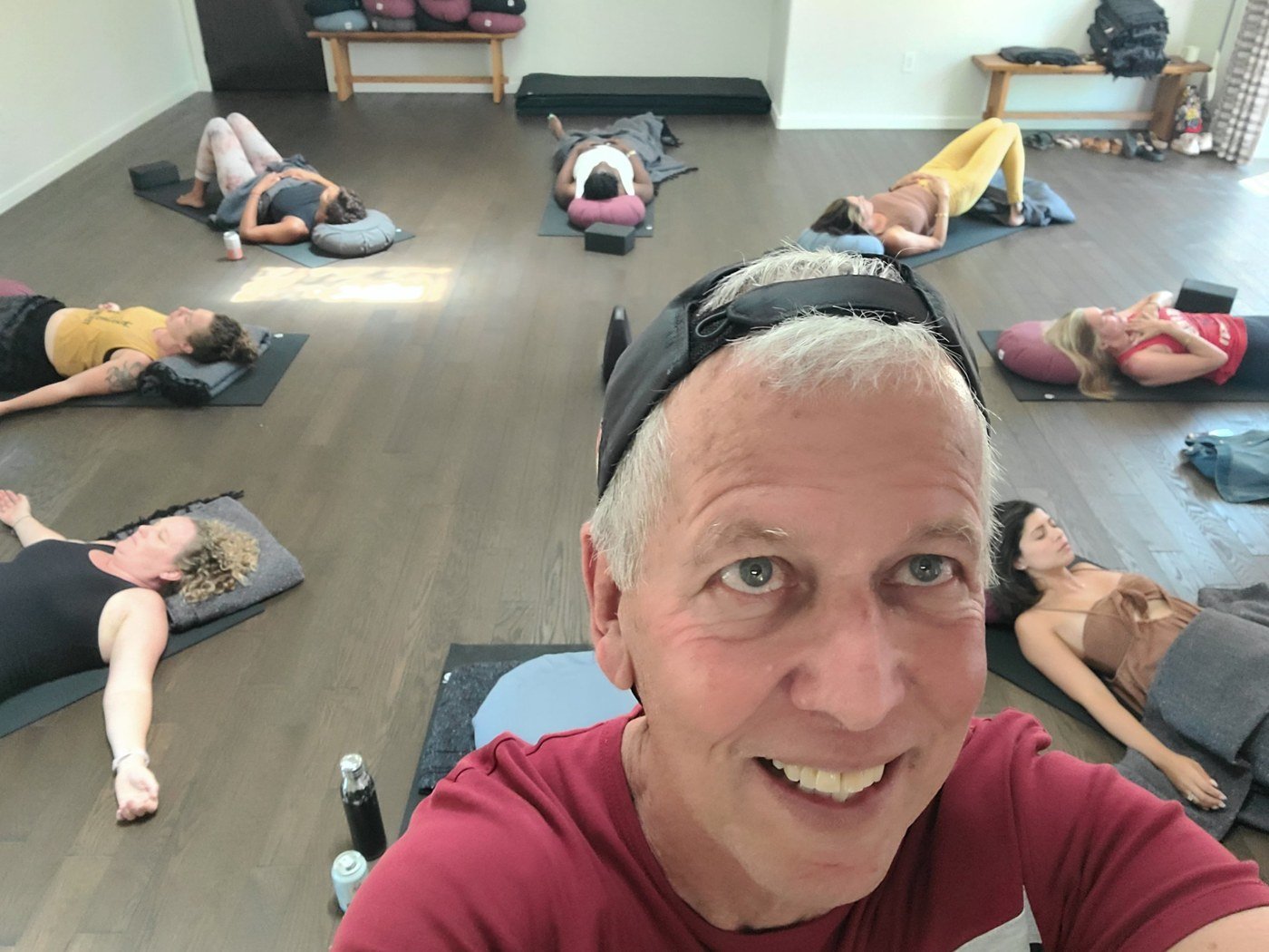 Roberto Suárez smiling at the camera while a group rests on mats behind him after a breathwork session