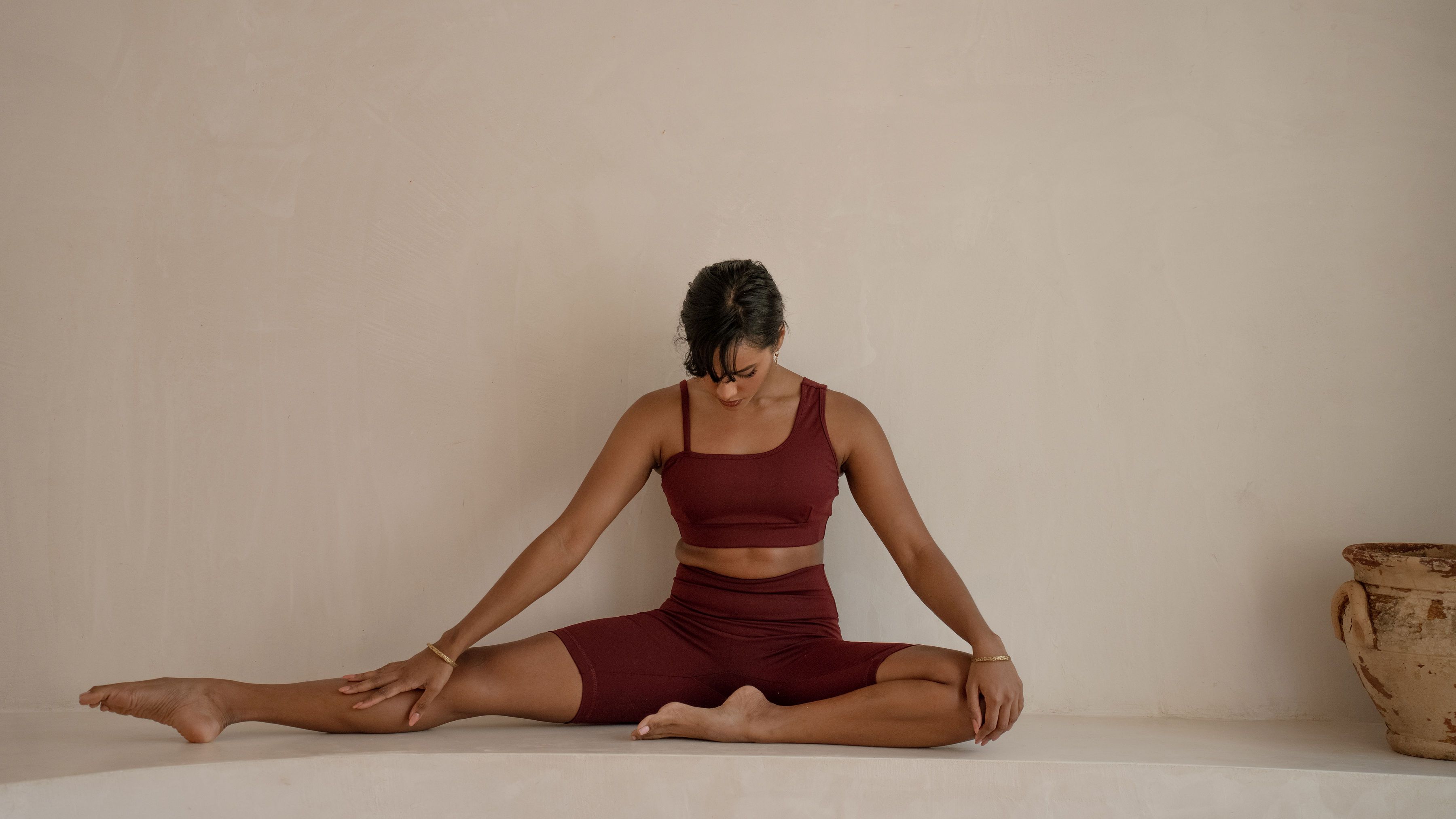Woman sstretching and breathing sitting on the floor next to a planter