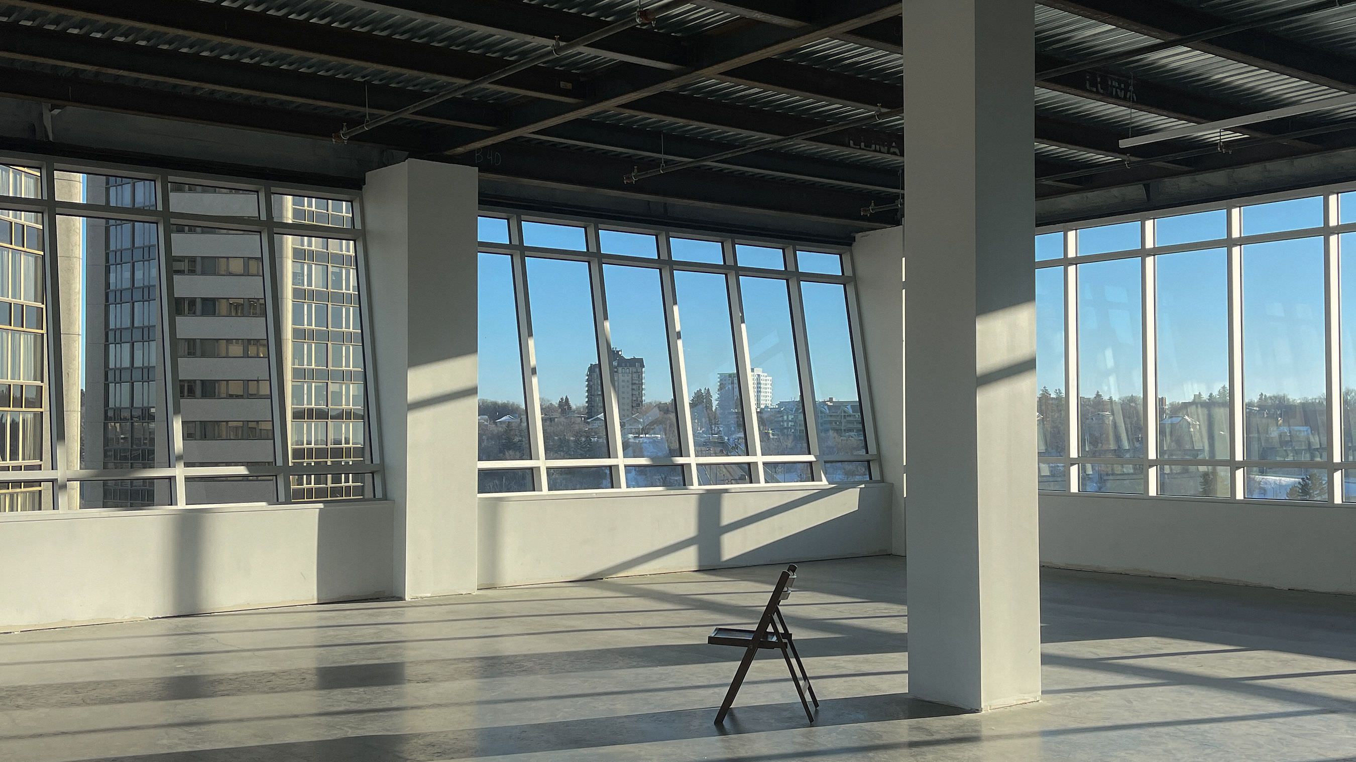 Warehouse room with big windows overlooking city and lone chair