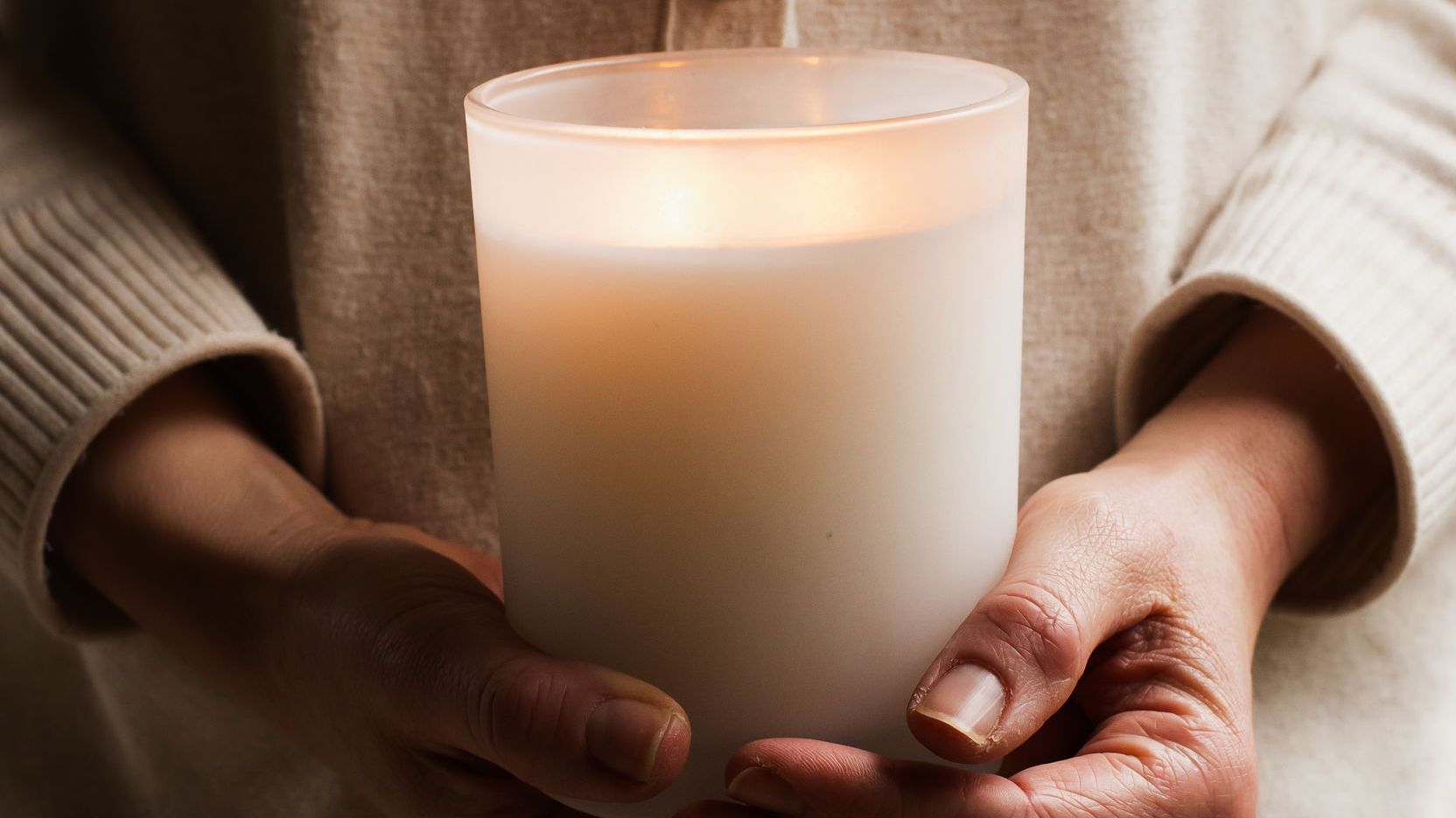 Hands holding a candle in soft warm light