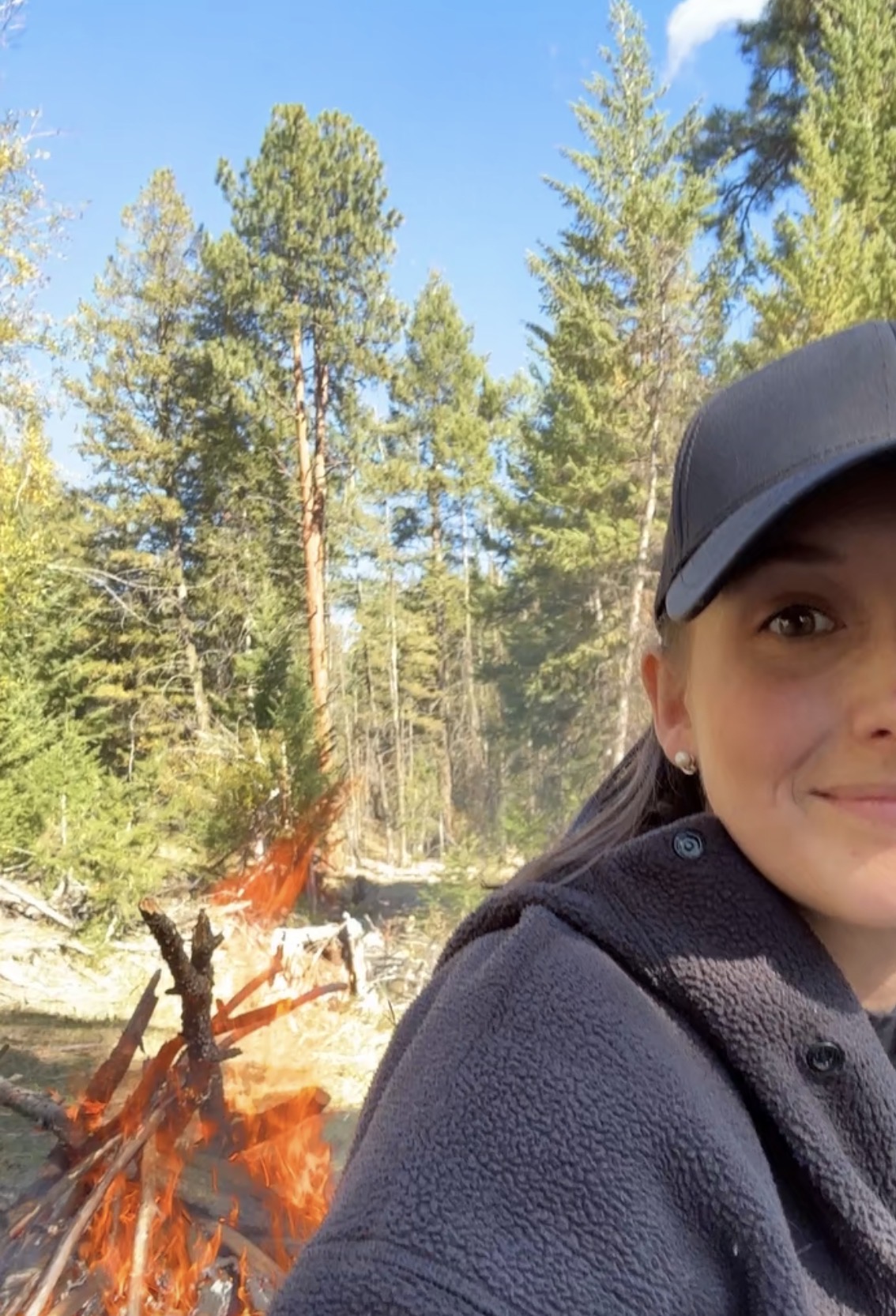 Kierstin smiling beside a bonfire in the forest