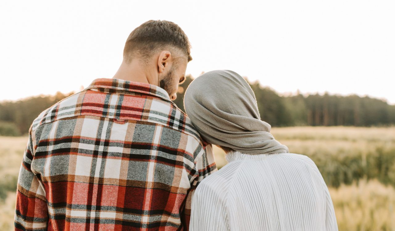 Couple leaning on each other in a field representing the integration work that brings Found(N)ation Unlocking YOU into real life and relationships