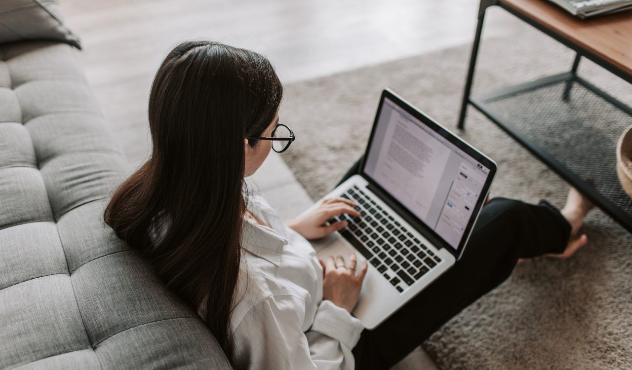 Woman working on laptop on sofa representing the weekly self-paced online learning modules inside Found(N)ation Unlocking YOU