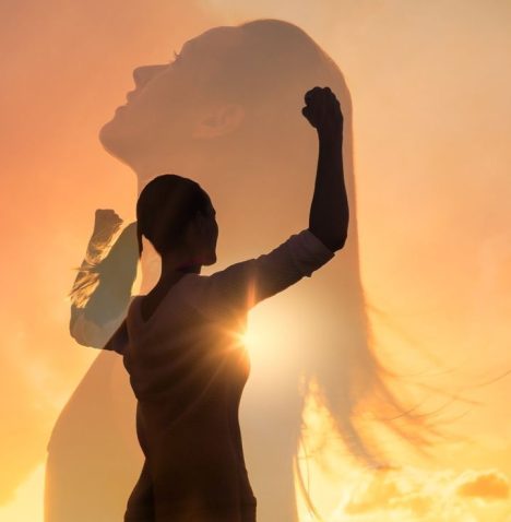 A woman rising into her power at sunset