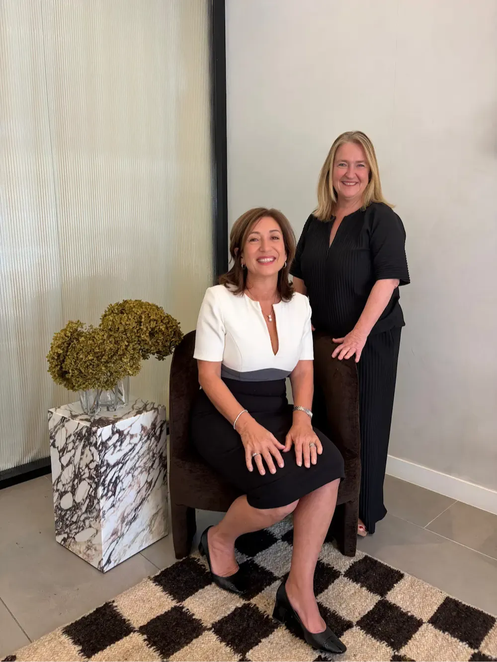 Two business coaches photographed together in a calm, professional studio setting.