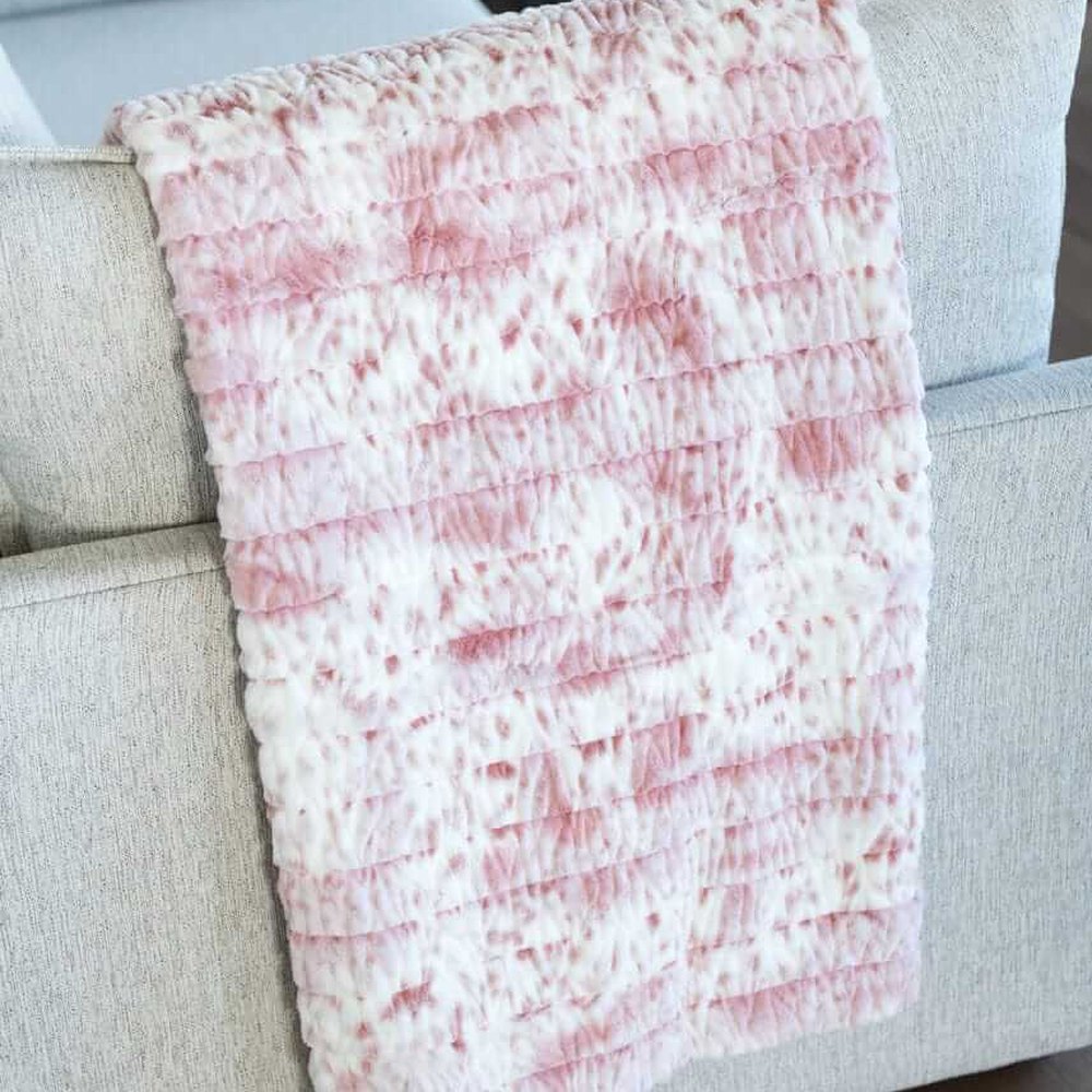 Soft pink and white Minky blanket draped over a sofa arm